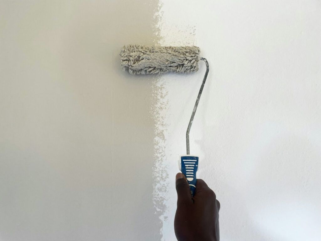 Person using a paint roller to paint a wall during a room renovation