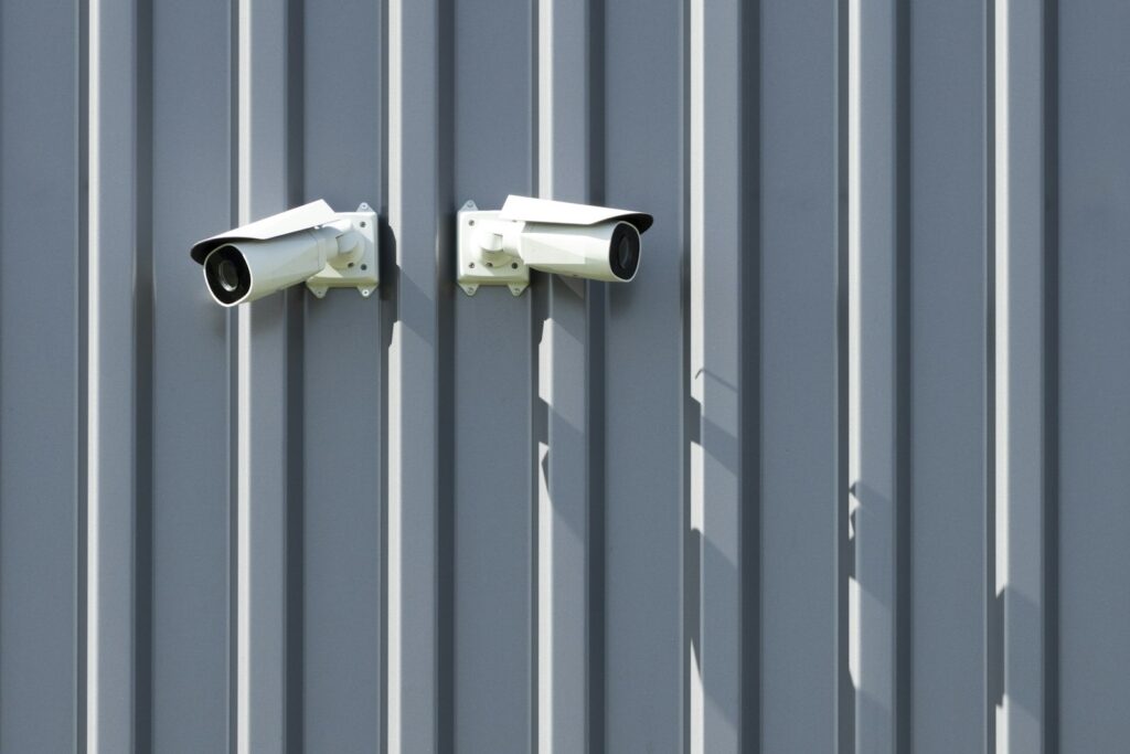 Two security cameras mounted on the side of a building, covering the premises