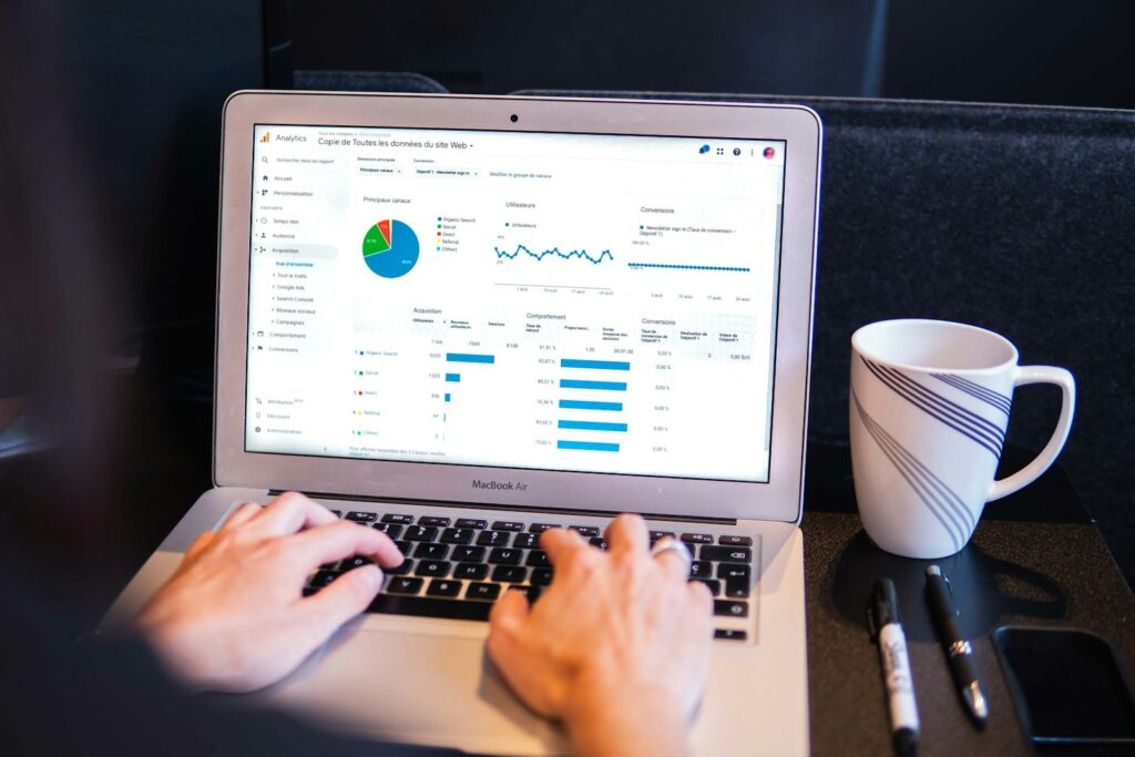 Person using a MacBook Pro on a black table with an analytics overview report on screen