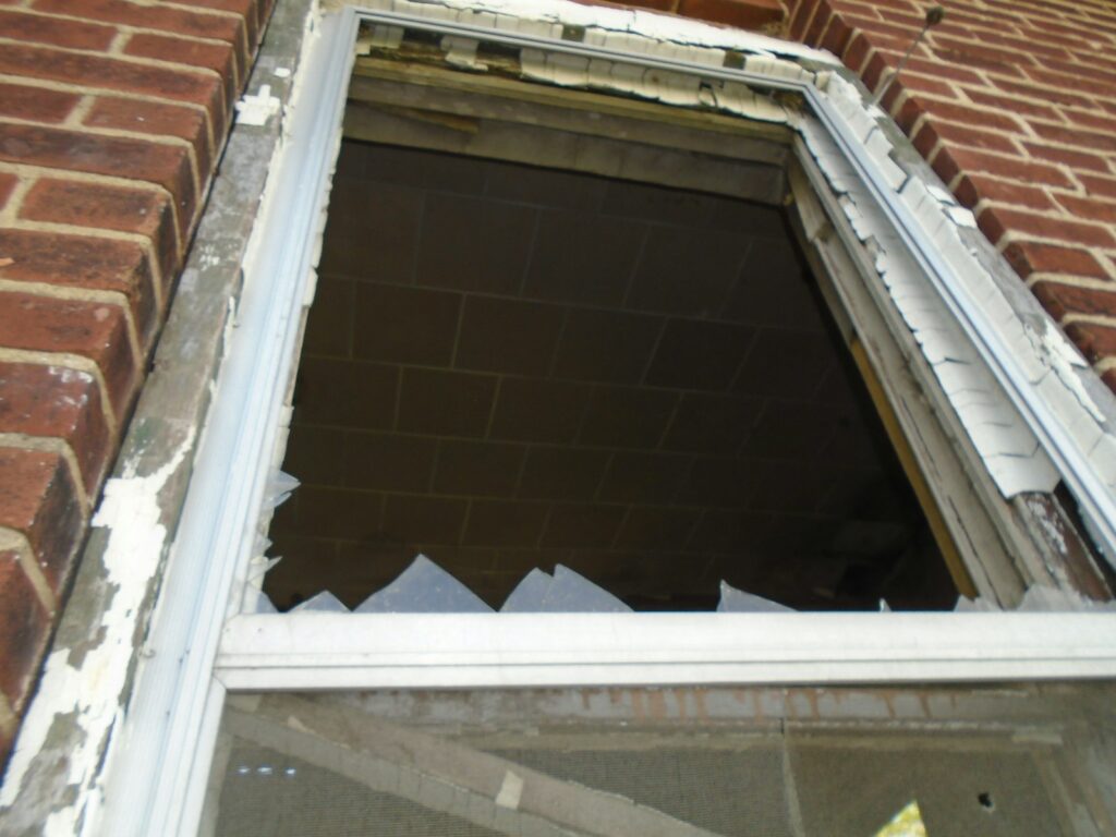 Broken window in the side of a brick building, in need of glass replacement