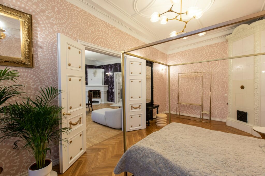 Elegant bedroom with a bed and a mirror on an intricately wallpapered beige wall